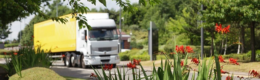 A truck driving on a road with flowers in the foreground