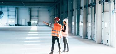 Two people in a large, empty warehouse