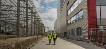 Two people walking on the sidewalk between two buildings