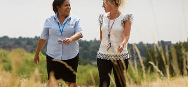 Two women walking and talking on a sidewalk