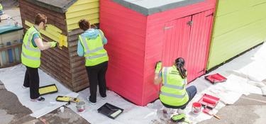 Three Prologis team members painting a building