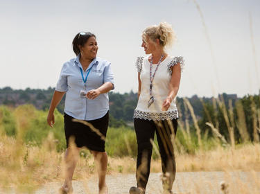 Two women walking and talking on a sidewalk