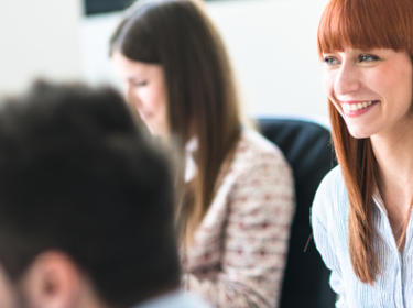 A woman smiling while in a meeting with team members