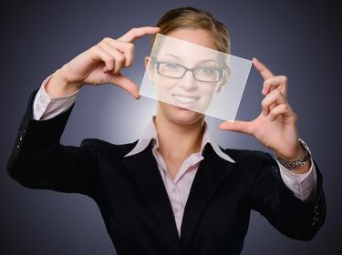 A woman holding up a piece of glass and looking through it