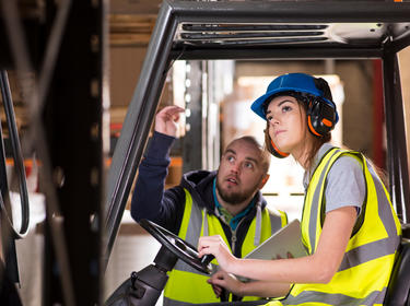 A woman receiving forklift instructions from a man