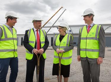 Four people at the ground breaking of a construction site