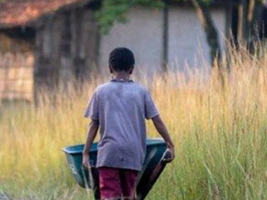 A boy with a wheel barrow heading to a house