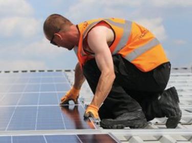 A man on a roof installing solar panels
