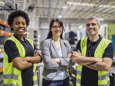Three members of Prologis team smiling confidently at the camera inside a warehouse