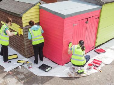 Three volunteers painting a shed