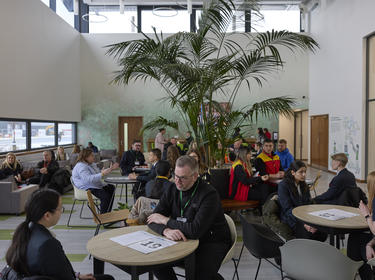 Group of adults sat at tables in communal area of The Hub at Prologis DIRFT