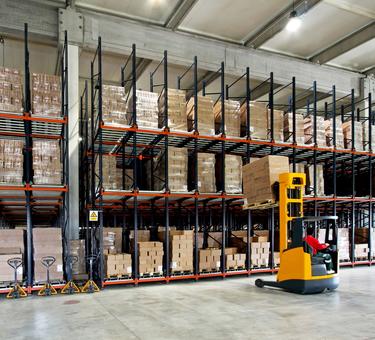 Forklift placing product on a rack in a warehouse