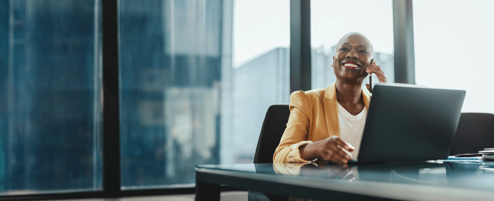 A woman working on a laptop, talking on the phone and smiling A woman working on a laptop, talking on the phone and smiling