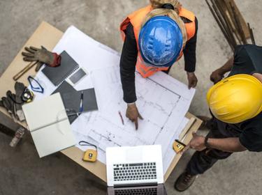 An overhead shot of two people looking at plans An overhead shot of two people looking at plans